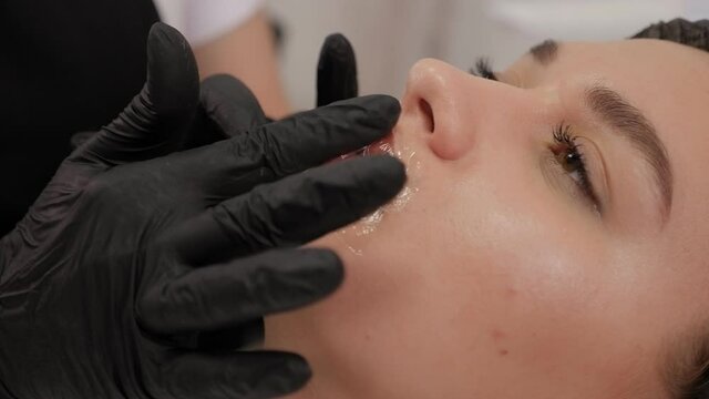 Applying anesthesia to the lips before permanent makeup.