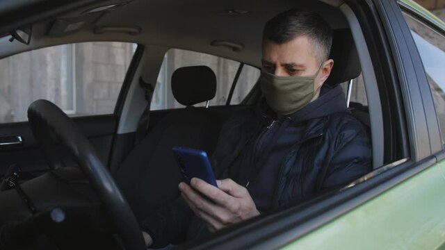 A man in a protective mask has fun shooting a street funny incident on a smartphone camera from a car window.