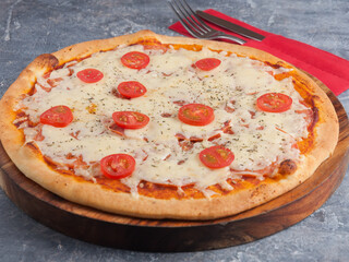 pizza Margarita with cherry tomatoes on a wooden Board