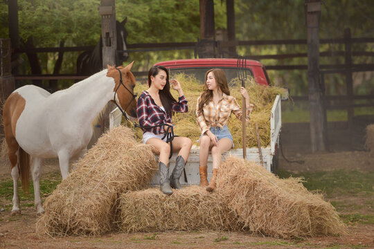 Two beautiful women sitting on the back of a truck talking, Thailand