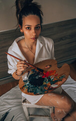 Beautiful talented female artist painting at her home.
