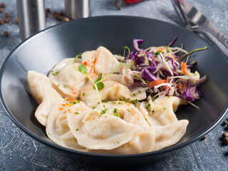 chicken dumplings with salad dressing in a dark plate