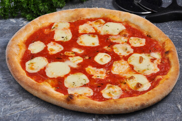 classic pizza Margarita on a gray background decorated with greenery