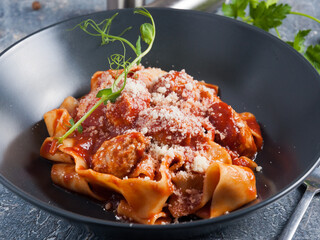 pasta with meatballs in tomato sauce in a dark dish