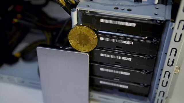 Concept of cryptocurrency mining. Mining Chia coins using hard disk drives. Gold bitcoin token in front of an HDD.