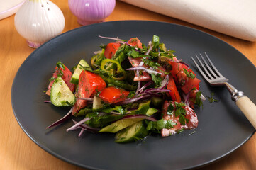 Georgian vegetable salad with cucumber tomatoes and onions on a dark plate