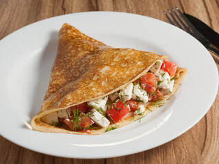 pancake with cheese and tomatoes on a white plate - obrazy, fototapety, plakaty