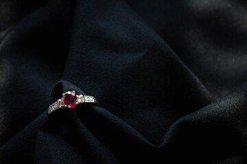 white gold ruby and diamond ring isolated on black fabric background