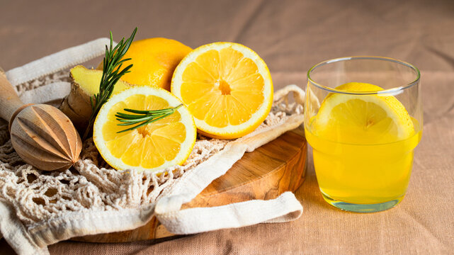 Refreshment  lemonade glass, orange fruit, wooden citrus squeezer , eco bage on linen tablecloth. Summer beverage for hot day concept.