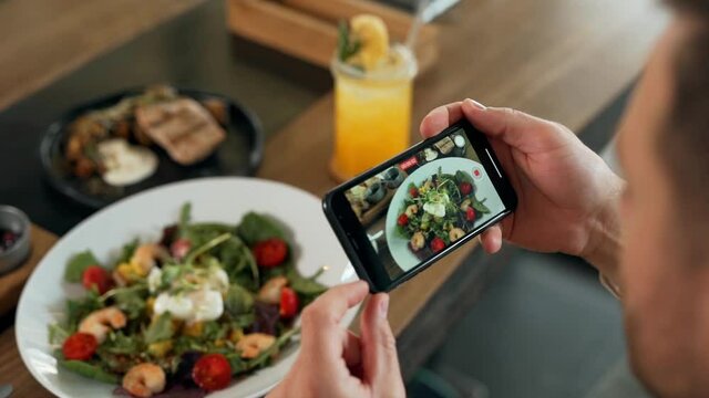 Close-up of smartphone screen taking pictures of dishes on table