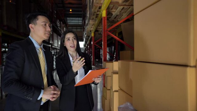 Confidence Asian businessman and businesswoman discussion business plan in distribution warehouse fulfillment center. eCommerce, business factory industry and freight transportation logistic concept.