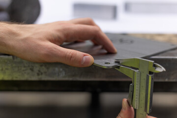 Qualitätskontrolle an einem Stück Metall mit dem Messschieber