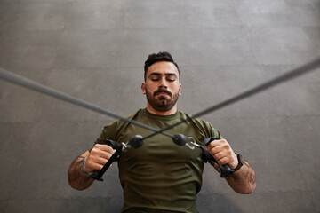 Top view high angle shot of muscular bearded guy chest cable crossover