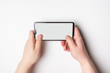 A phone with a white screen. Free space on the screen. The hand holds the phone horizontally.