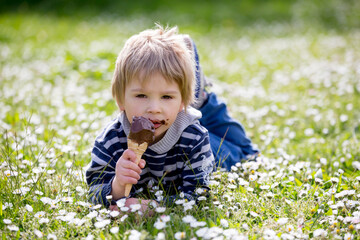Cute blond child, boy, eating ice cream in the park