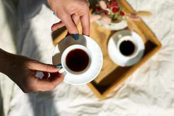 Woman sitting on the bed, and drink coffee during the morning sunlight