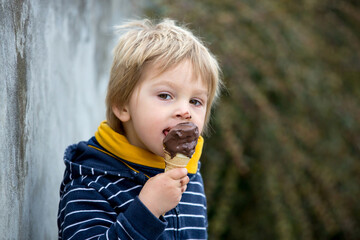 Cute blond child, boy, eating ice cream in the park