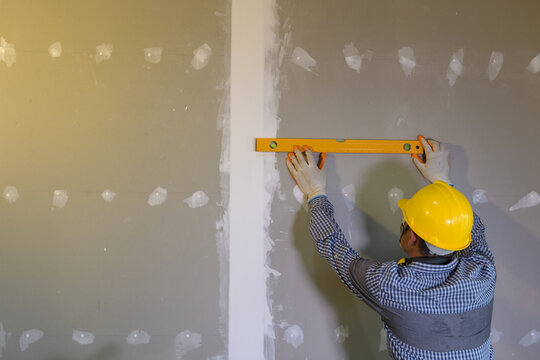 Construction worker using a spirit level on a building site, Thailand