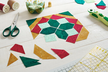 Pieces of fabric laid out in the shape of a patchwork block, sewing and quilting accessories.