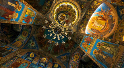 Fototapeta na wymiar Interior of the Cathedral of the Savior on Spilled Blood. Saint-Petersburg. Russia. Colored frescoes on the vaults of the ceiling. There is a chandelier. Background.