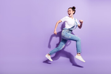 Fototapeta na wymiar Full size profile side photo of young excited girl happy smile jump go walk run hurry isolated over violet color background