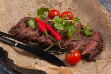 beef steak on parchment decorated with pepper and herbs