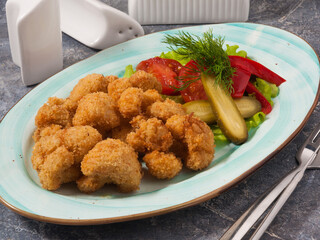tasty cauliflower fries with vegetable dressing on a grey background