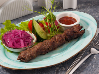 Lula veal kebab with tomato sauce, onion and vegetables