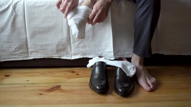 A man puts on white socks and shoes,in the morning a businessman man is going to work wearing socks sitting on the couch