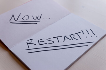 White page of notebook, written in black "now ... restart!" in English 