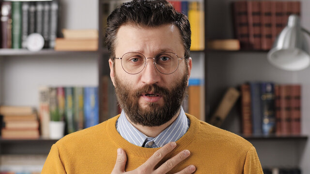 Sorry, man is apologizing and regret. Sad bearded male teacher or businessman with glasses looking at camera and sincerely apologizes and says sorry