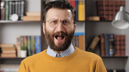 Surprised, screaming man. Indignant bearded male teacher or businessman with glasses looks at...