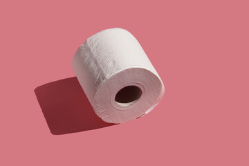 A roll of white toilet paper on a pink surface