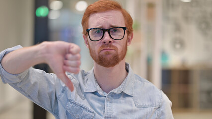 Disappointed Young Redhead Man doing Thumbs Down 