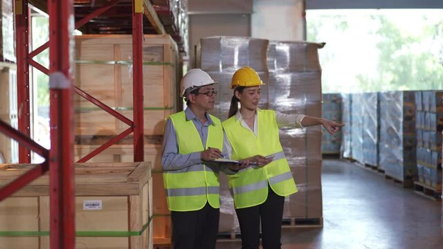 Asian male and female warehouse worker working checks inventory storage box on pallet in distribution fulfillment center. eCommerce, B2B global business and freight transportation logistic concept.