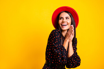 Photo of shiny impressed lady dressed clothes cap looking empty space arms together cheek isolated yellow color background