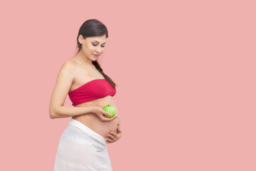 Fototapeta na wymiar young pregnant woman holds a green apple