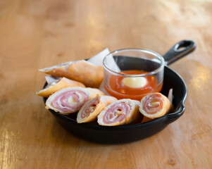 Spring rolls with ham and cheese served with hot sauce.