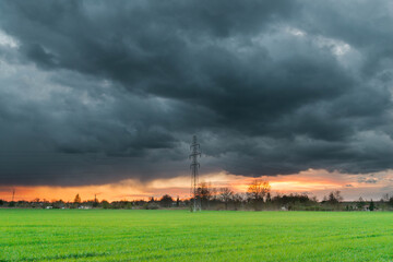 Obraz na płótnie Canvas Elektryczny słup wysokiego napięcia na tle pokrytego ciemnymi, groźnymi chmurami nieba.