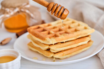 Honey pouring on a fresh Belgian waffles.