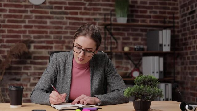 Young female sit in office thinking about works, solving business issues and get a new idea.Creative telework, brainwork concept.Beautiful young brunette business woman in glasses sitting and thinking