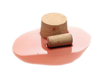 Red wine puddle and cork isolated on white background