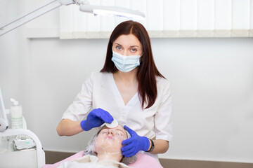 Facial treatments, professional skin cleansing. A young teen girl at appointment of female young confident doctor dermatologist, making face cleaning and acne treatment