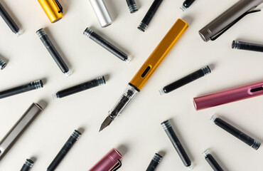 Ink pens and ink cartridges are scattered on the table.