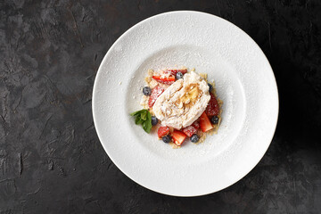 dessert at black background. Anna Pavlova meringue with low-fat whipped cream and fresh strawberry