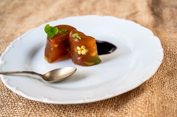 2 piece of vegetable aspic on white plate on jute.