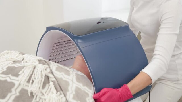Woman beautician connects and adjusts the device for photo peeling.