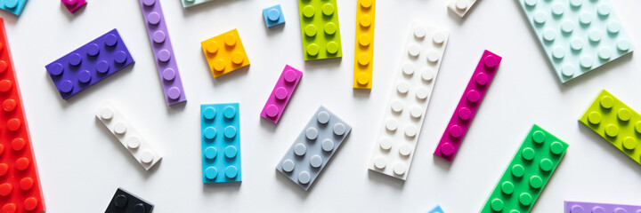 Multicolor plastic blocks on white background. Top view, banner size, many colors.