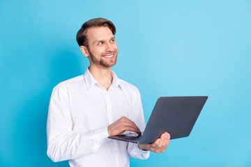 Photo of dreamy young man look empty space good mood imagine hold laptop isoalted on blue color...
