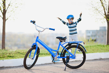 Cute child in helmet and protection stands near his bike